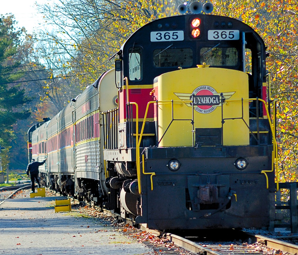 Yellow and burgundy Cuyahoga Valley Scenic Railroad train at a station in fall